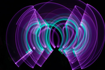 Curved abstract shape made with a light saber violet. Lightpainting session at night. Leds light effect. Background for wallpaper.