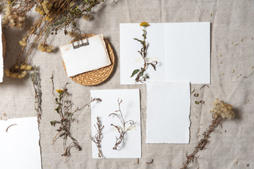 Autumn atmospheric mockup with dry plants , papers on grey textile background. Top view, flat lay. Wedding stationary. Perfect for presentation of your invitation, menu, greeting cards