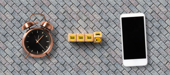 cubes with car symbol and text TAXI and a smartphone on stone background