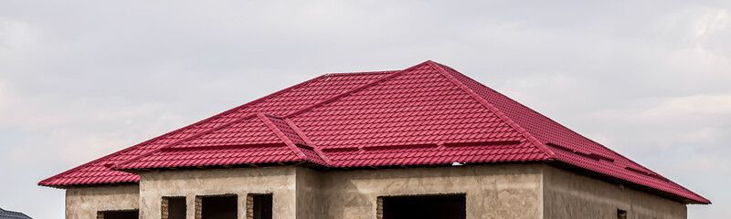 The roof of the house from a metal profile against the sky.
