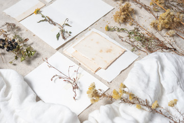 Wedding invitation mockup with dry plants , old papers on grey textile background. Top view, flat lay. Wedding stationary. Perfect for presentation of your invitation, menu, greeting cards