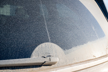 Grit and dust covered rear window of a van with wiper track