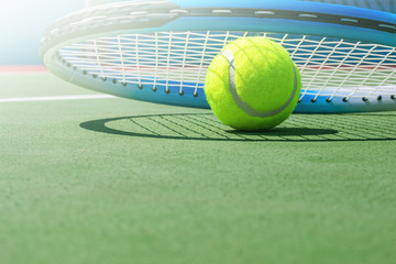 Tennis racket and tennis ball on court.