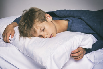Sleeping boy in bed with pillow and blanket