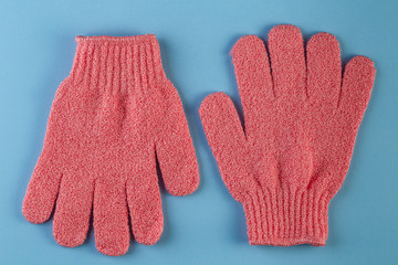 A pair of pink massage gloves for shower on pink background. Gloves for use in the shower for...