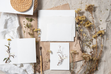 Wedding invitation mockup with dry plants , old papers on grey textile background. Top view, flat lay. Wedding stationary. Perfect for presentation of your invitation, menu, greeting cards