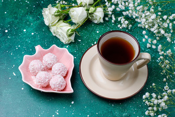 March 8 Women's Day card with white flowers,sweets and a cup of tea on dark background.