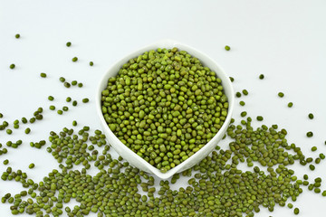 dry mung beans in a ceramic bowl isolated on white background