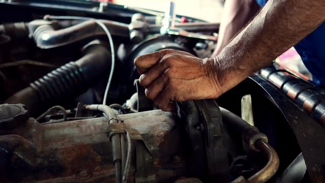 Mechanic man repairing car engine in garage.