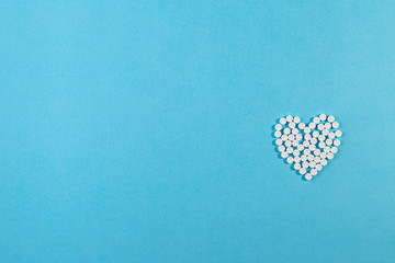 Heart shape made of pills on blue background. Mock up for advertising or other ideas. Medical and healthcare concept. Copy space. Empty place for text