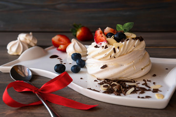 Cupcake with white cream and fruit on a wooden background