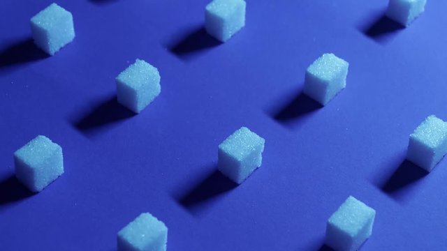 A 4K tilt up view of a unique cubic background with white sugar cubes arranged in rows on a dark blue background, 3D effect.