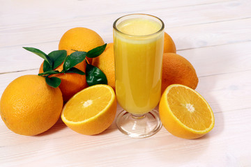A glass of fresh orange juice and orange fruits on a wooden table. Healthy food.  