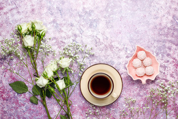 March 8 Women's Day card with white flowers,sweets and a cup of tea on light background.