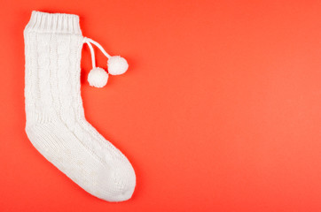 White socks with pom poms on red background composition.