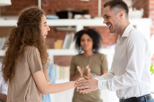Smiling executive manager shaking hand of happy businesswoman intern