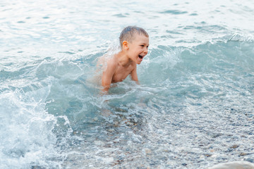 little girl in a swimsuit splashing her legs in the sea