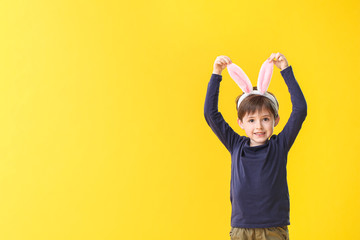 Little boy with bunny ears on color background