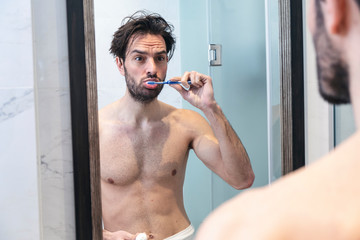 Fototapeta na wymiar Single handsome man washing his teeth in the bathroom, morning routine.