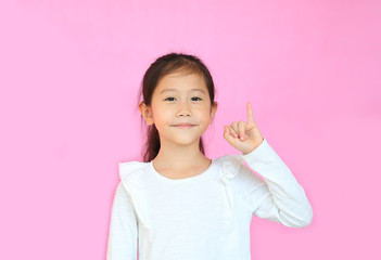 Beautiful asian little girl showing pinkie finger isolated on pink background. Portrait of smiling...