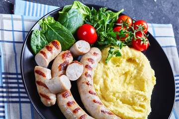 French potato aligot on a black plate with sausage