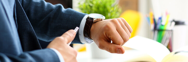 Man in suit and tie check out time at silver wristwatch closeup. Show and point with finger waste...