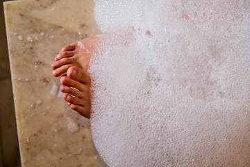 Women's feet covered with foam after massage in the Turkish bath