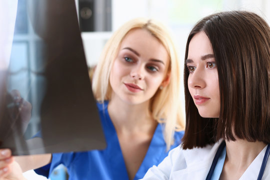 Group of beautiful female doctors hold in hand and look at xray photography to detect problem. Bone disease exam medic assistance cancer aid healthy lifestyle ill test hospital practice concept