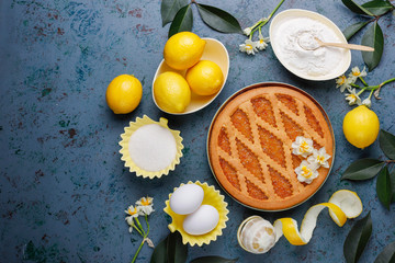 Delicious lemon pie with fresh lemons on dark background,top view