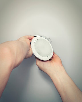 Installing spots. Electrician  installing or replacing spot light lamp into ceiling. Installing a spot in a stretch ceiling.