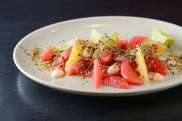 Citrus salad with smoked salted salmon fish, grapefruit, orange, sesame seeds and spices served on white plate