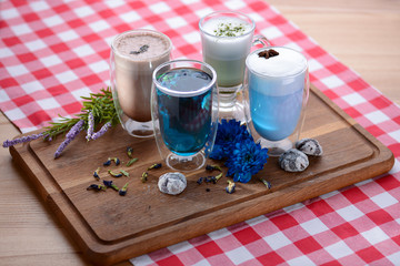 Top view of a cup of butterfly pea blue tea, pea flowers, blue pea for healthy drinking on dark wooden cutting board
