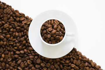 white cup on coffee beans on a white background, top view