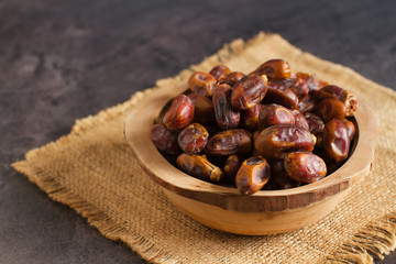 Sweet dried dates fruit in a wooden bowl and on the table