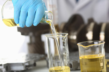 Male hands in protective gloves hold test tube in hands produces chemistry test of motor oil...