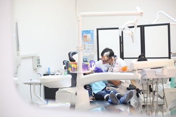dentist is diagnosing the child while assistant in dental clinic