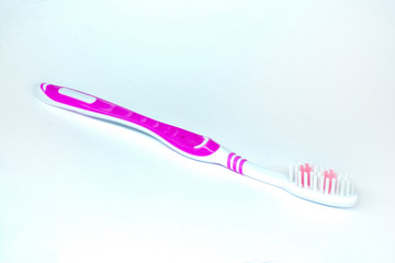 Toothbrush on a white background. Pink toothbrush for cleaning teeth and gums. Personal hygiene.