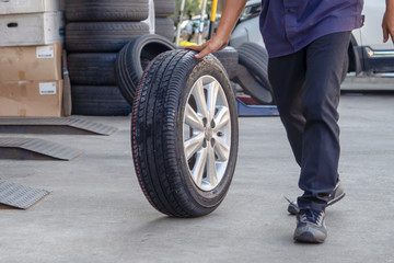 Professional car mechanic with tires in the auto repair center