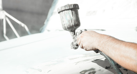 Spray gun in the hand of a painter. Painting car details