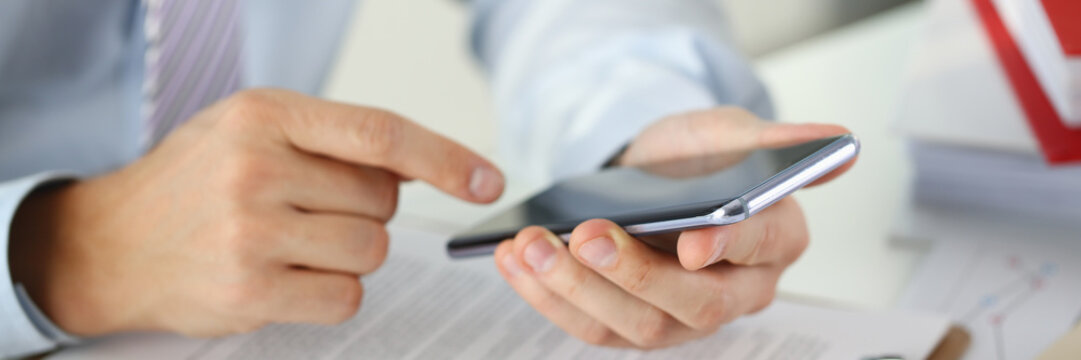 A businessman holds a new smartphone in his hand The mobile application market shows a display you can insert your image for advertising or financial statistics.