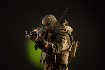 soldier militia saboteur in military clothing with a Kalashnikov rifle on a dark background