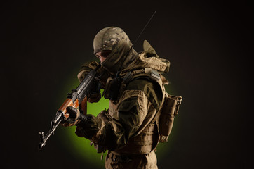 soldier militia saboteur in military clothing with a Kalashnikov rifle on a dark background