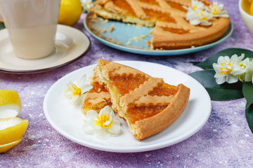 Delicious lemon pie slices with fresh lemons and a cup of tea on light background,top view