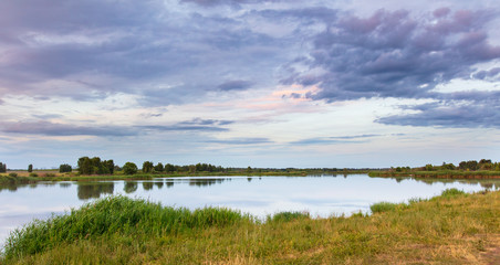 Fototapeta na wymiar Lake in the grass at sunset.