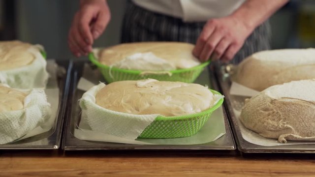The baker spreads the raw bread out of the molds and prepares it for baking in the oven