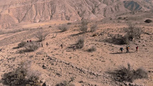 Aerial drone shot above group of hikers crossing valley and mountains in Jordan, Dana Biosphere Reserve