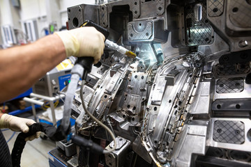 Engineer doing maintenance on the injection mold after production by dry nitrogen, industrial...