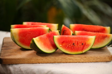 cutting fresh ripe watermelon into pieces with a knife on a wooden table