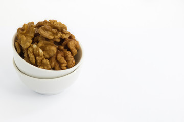 Obraz premium Peeled walnuts in white bowl on white background
