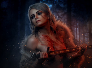 Beautiful naked woman with blood stained skin holding a long sword in night forest. Fantasy...